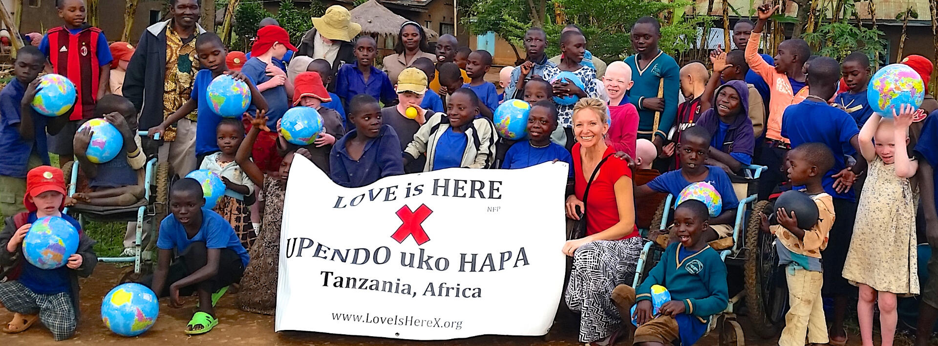 picture of Tanzanian children holding a "Love Is Here" banner
